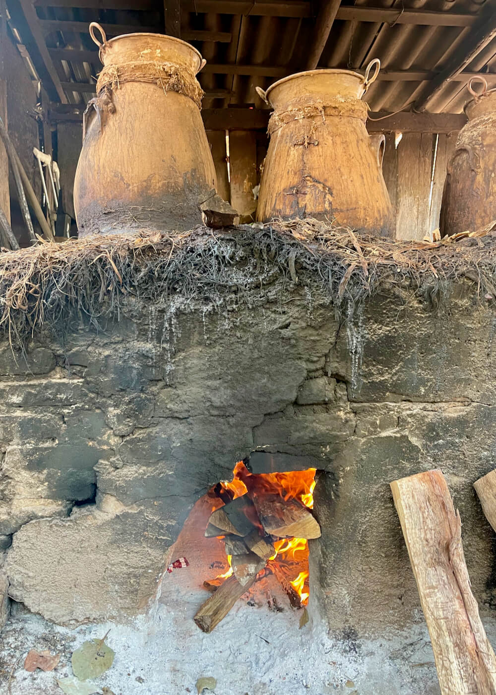 A raging fire heats two clay pot stills