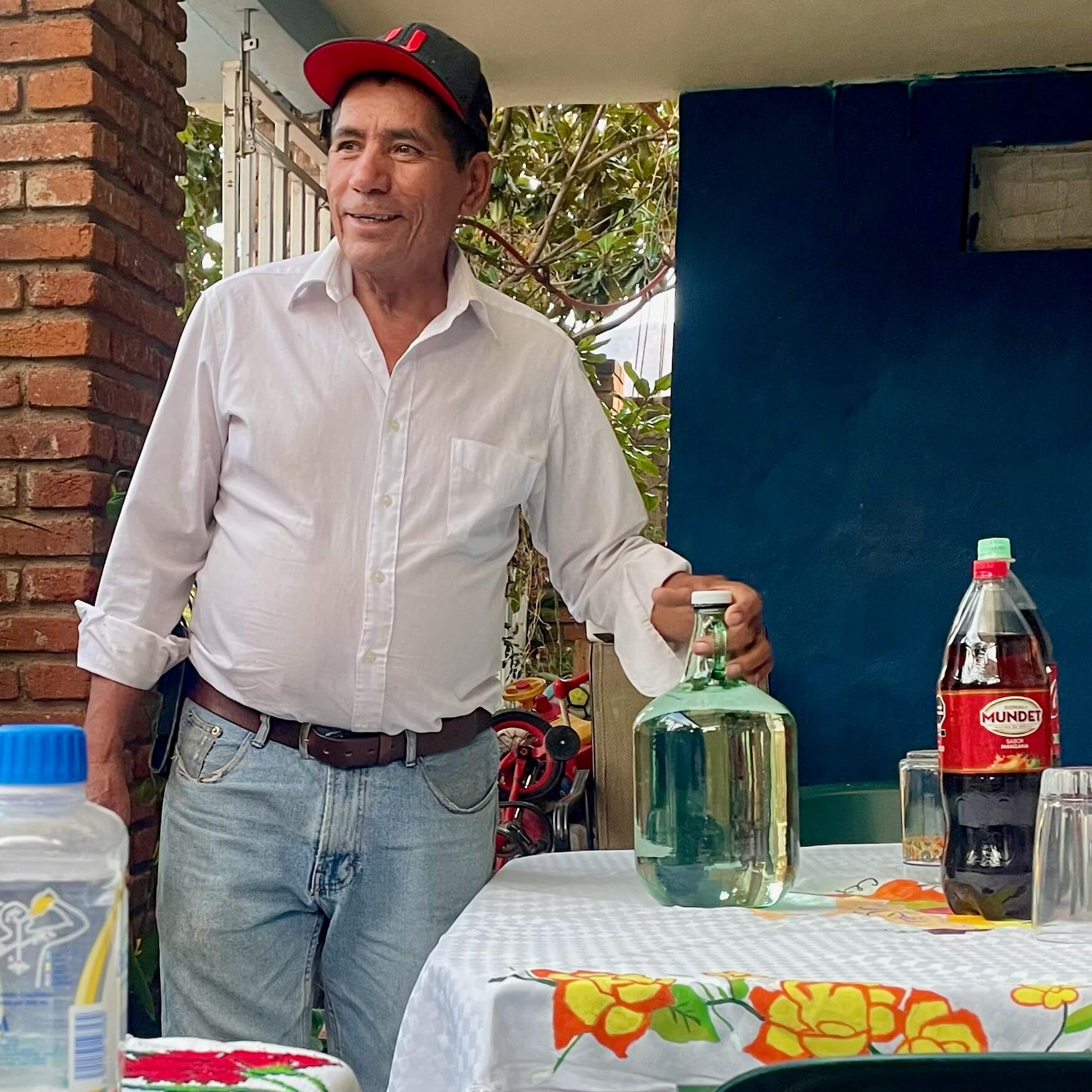 Mezcalero Isidro Rodriguez holding a bottle of mezcal near a table