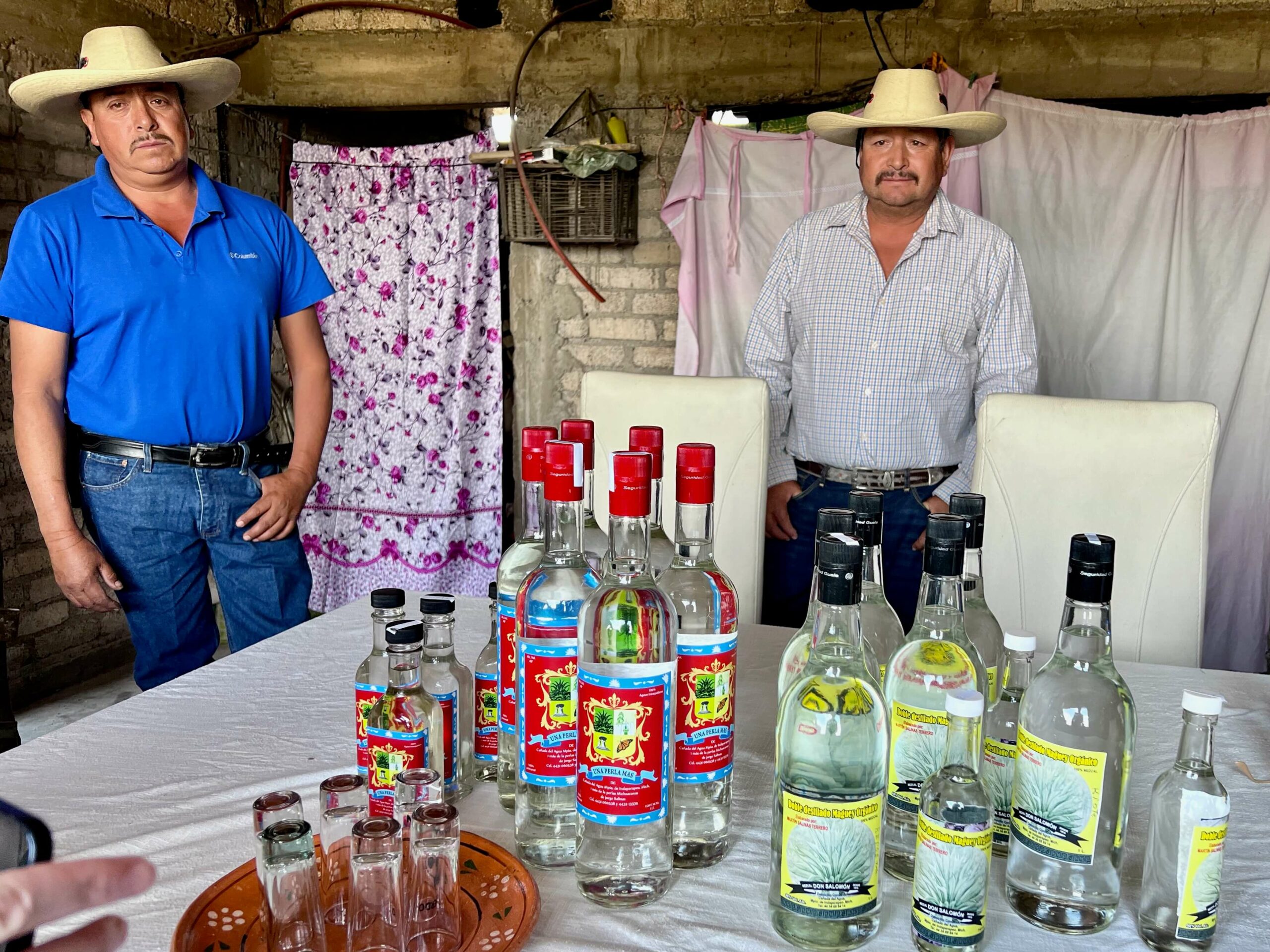 The Salinas brothers standing behind a table of mezcal bottles
